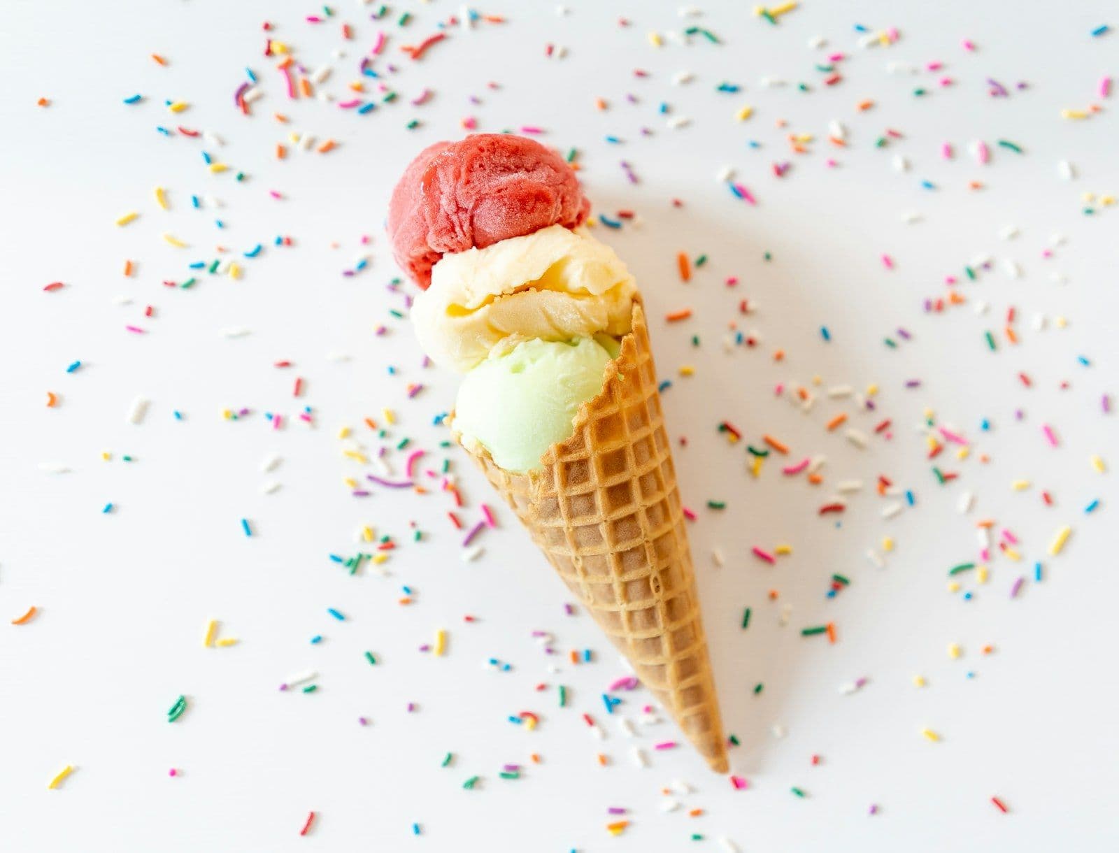 Three scoops of ice cream in a waffle cone with sprinkles